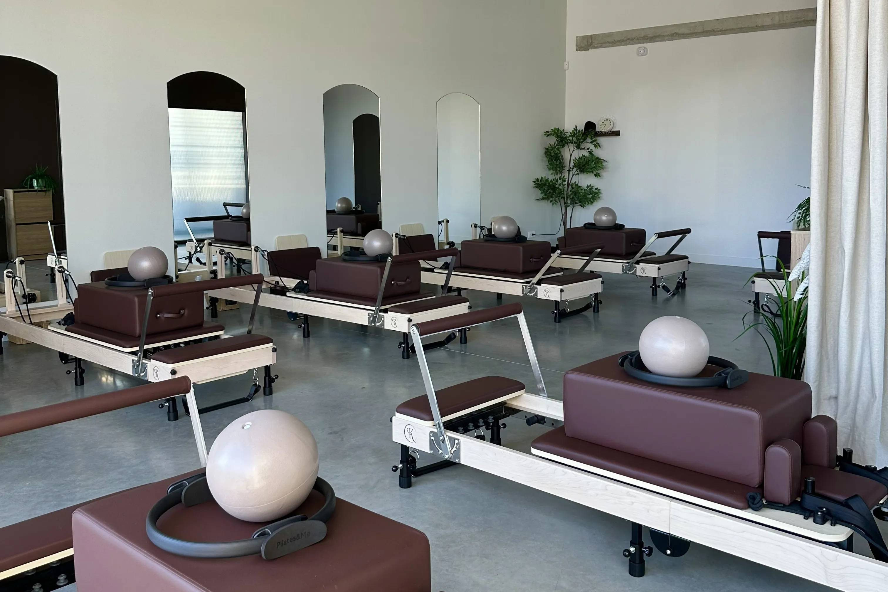 La salle Reformer du Kaizen Pilates Club à Plaisance-du-Touch : reformers alignés face aux miroirs arrondis, ballons et cercles de Pilates posés sur les machines
